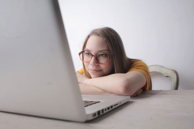 Woman wearing glasses resting and watching a laptop.