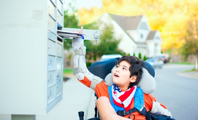 Boy living with disability getting mail from mailbox 