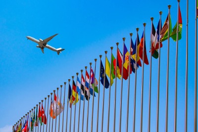 Image of aeroplane flying over row of international flags