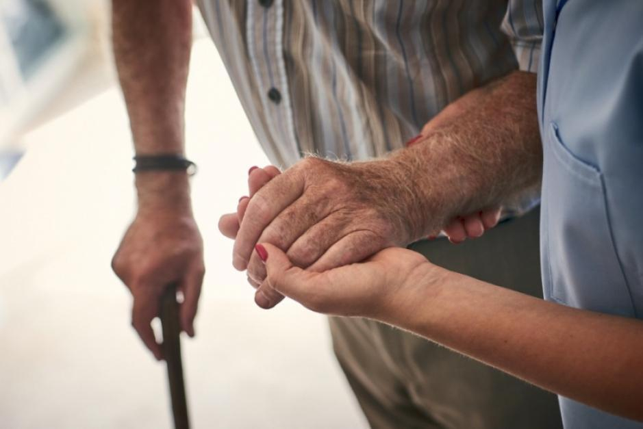 A female nurse supporting an elderly man to walk