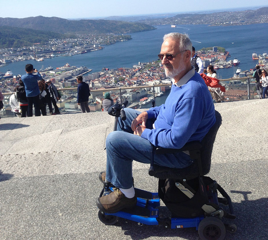 Man sitting in mobility scooter overlooking a beautiful ocean vista