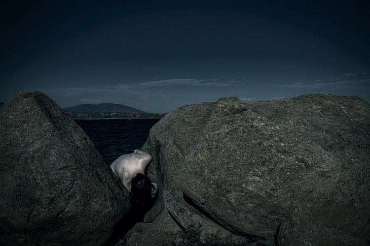 Naked figure wedged between two large rocks
