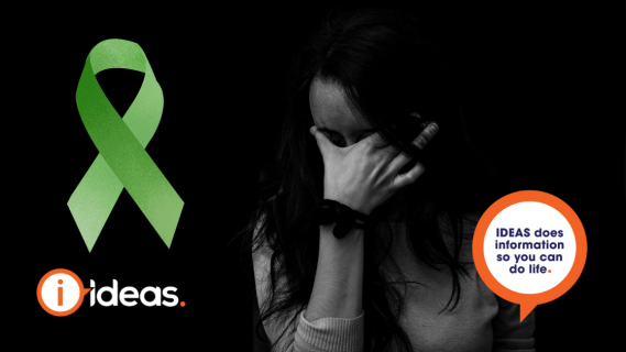 Woman looking sad and holding head in her hands and a green awareness ribbon