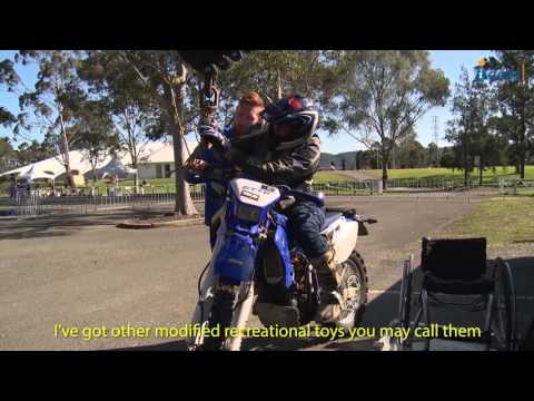 Man getting onto a motor bike from his wheelchair