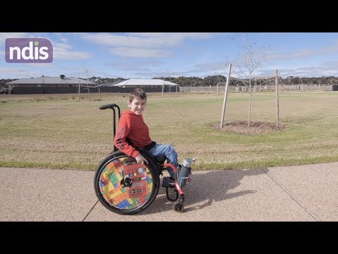 Little boy in his wheelchair on the footpath in the park