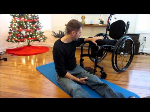 Man sitting on floor next to wheelchair