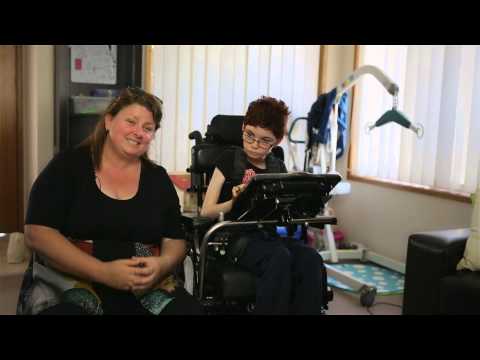 Young girl in wheelchair sitting next to her mum