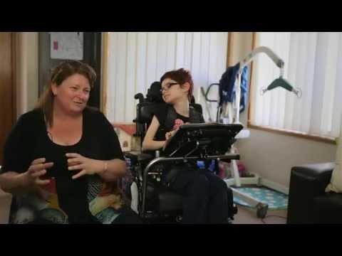 Young girl in a wheelchair sitting next to her mum