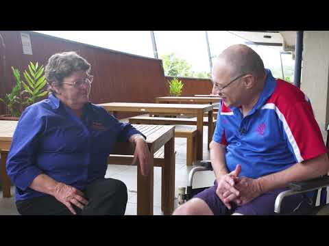 Man sitting in a wheelchair with lady sitting on a bench talking