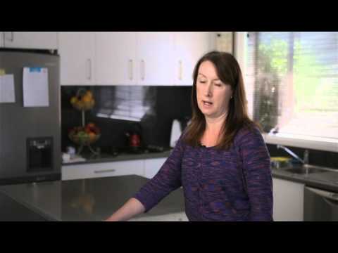 Woman standing in her kitchen talking 