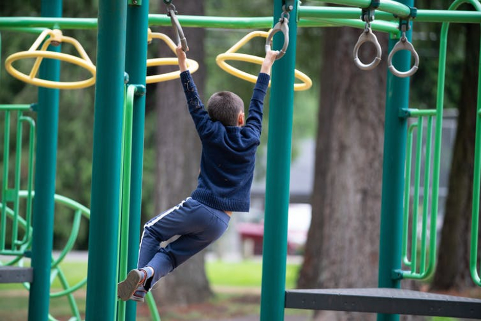 Image of boy winging on monkey bars