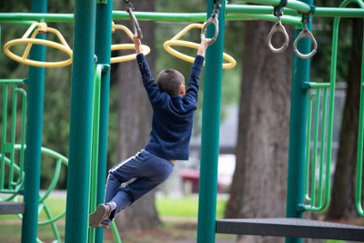 Image of boy swinging on monkey bars