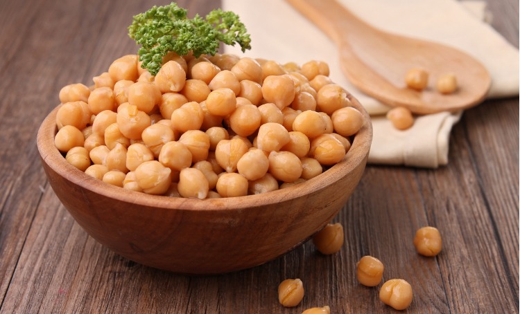 wooden bowl overflowing with chickpeas topped with parsley