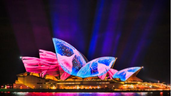 Image of the sails of the Sydney Opera House illuminated in electric blues and pinks.