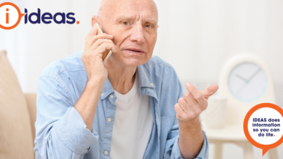 A senior man in a blue shirt is on the telephone.