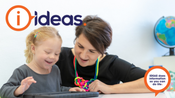 An Image of a toddler girl with disability alongside her therapist, on a electronic device