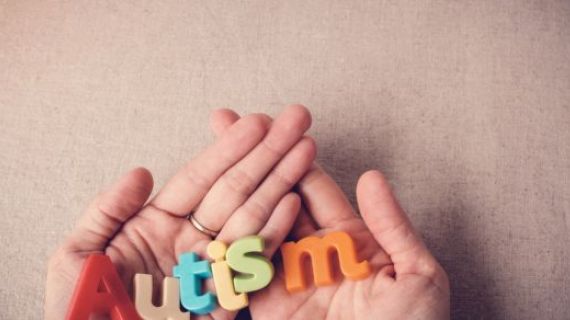 AUTISM written with colourful alphabet magnets, resting on hands