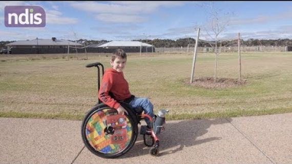 Little boy in his wheelchair on the footpath in the park