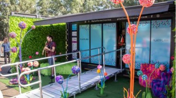 Exterior shot of PLATFORM art installation space with brightly coloured three dimensional organic shaped works with long tendrils and fuzzy balls by artist Bliss Cavanagh