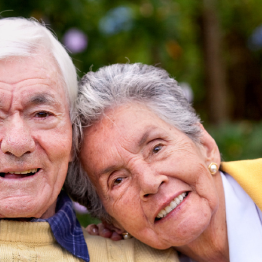 An older couple, the lady is leaning her head on the gentleman's shoulder.