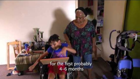 Woman with a child painting using mouth in the lounge room