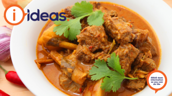 A white bowl with beff, potato, onion in a curry sauce and garnished with coriander.