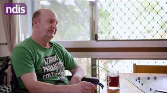 Man sitting at a table with a board game set up and a soft drink
