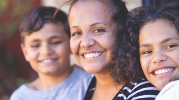 Image of smiling Aboriginal woman with two kids on either side of her.