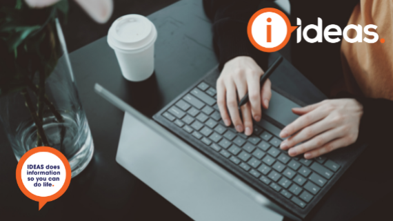 Woman typing on laptop with pen in hand