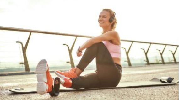 Image of a young woman with a disability on a yoga mat doing stretches