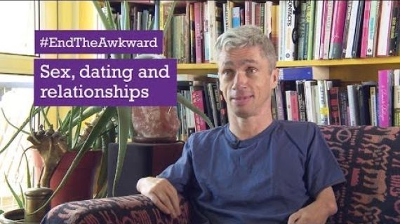 Man sitting on lounge with bookcase behind him