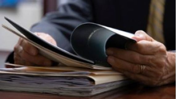 A pile of paperwork with hands flicking through the pages