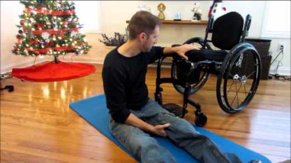 Man sitting on floor next to wheelchair