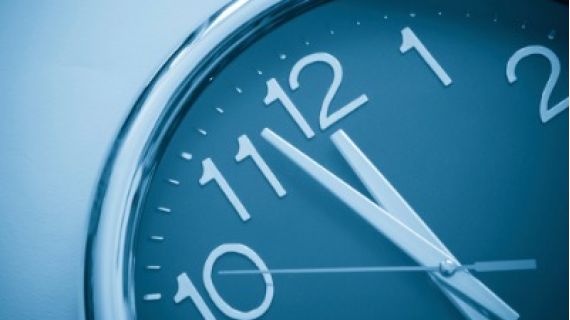 Image of analog clock face with hands approaching the stroke of 12.