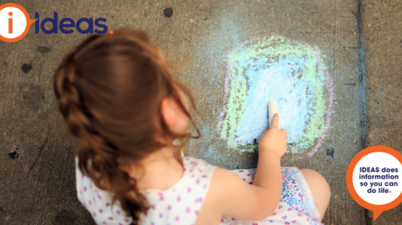 An image of a young girl drawing with chalk on concrete