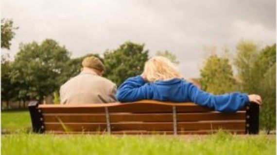 Two people sitting on a park bench, view from behind