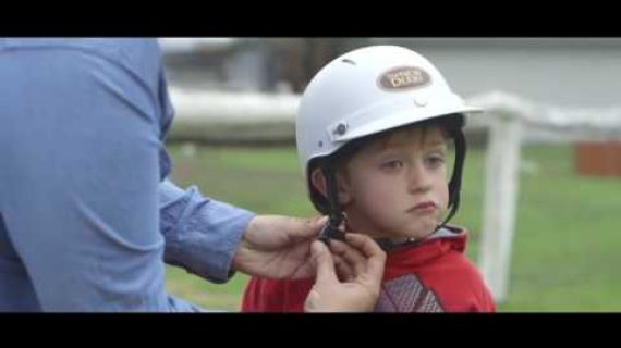 Person doing up a child's helmet