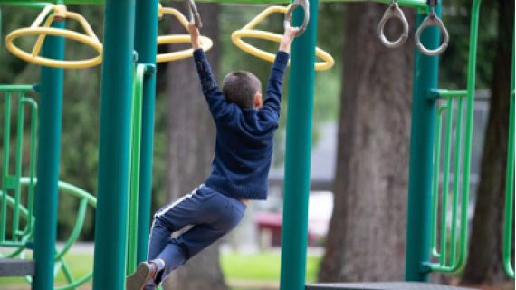 Image of boy swinging on monkey bars