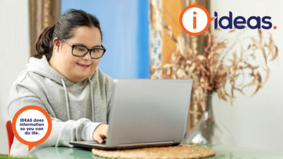 A girl with glasses and dark hair with intellectual disability is using a laptop computer