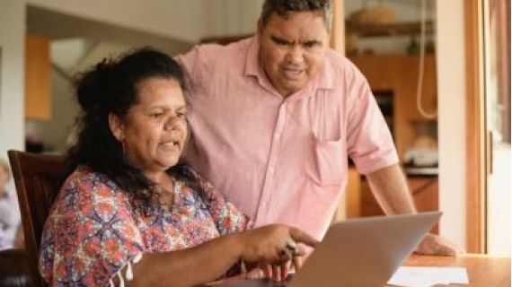 Image of elderly couple looking at a laptop computer inside their home.