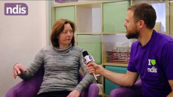 Man holding microphone to woman sitting in a chair