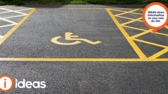 An image of a disability parking space. Within the space is a yellow painted symbol of person in a wheelchair. Beside the parking space are two areas with cross marks to illustrate clear space on each side of the parking space.
