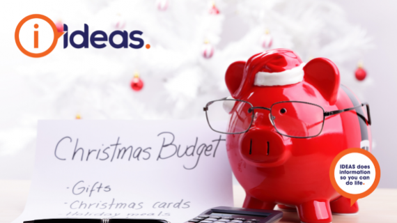 A red piggy bank wears glasses, next to a black calculator and list with "Christmas Budget"