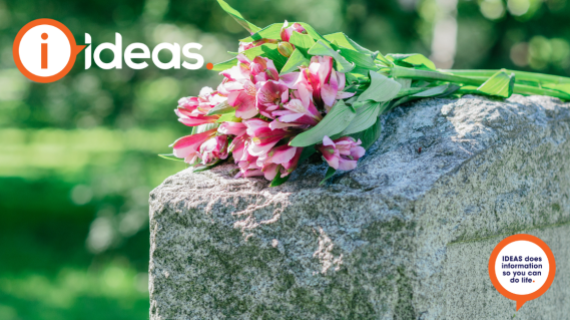 An image of a headstone with pink flowers laid in respect.