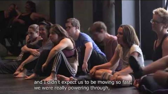 Group of people sitting on the floor of a dance studio