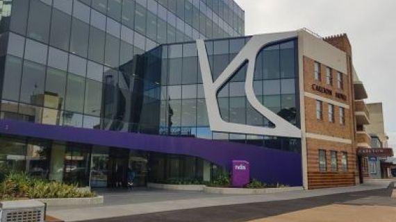 A female nurse supporting an elderly man