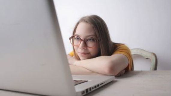 Woman wearing glasses resting and watching a laptop.