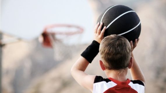 A young boy lining up a basketball shot