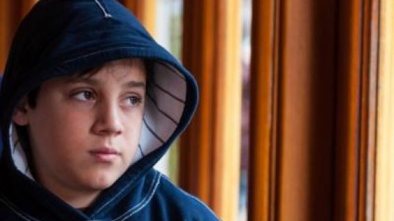 Image of a young boy with a hoodie looking thoughtful