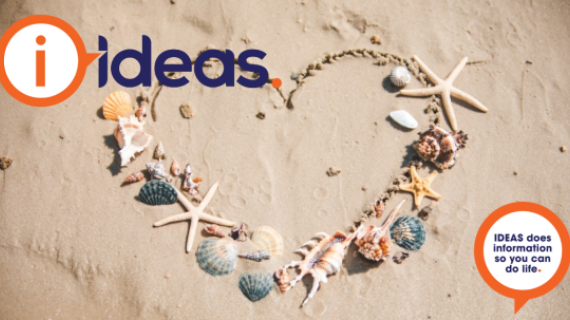 A photograph of a heart drawn in the sand of a beach. Around the edges of hte heart, decoratively placed, are a variety of seashells, and starfish.